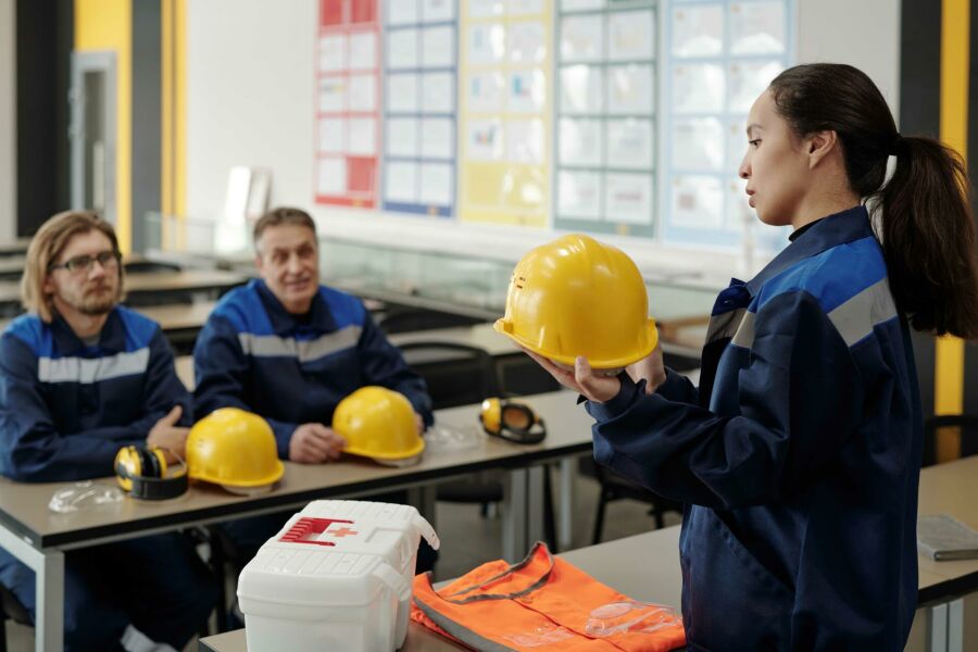 Imagem /////young-pretty-female-worker-uniform-standing-front-her-male-colleagues-while-describing-purpose-usage-protective-helmet