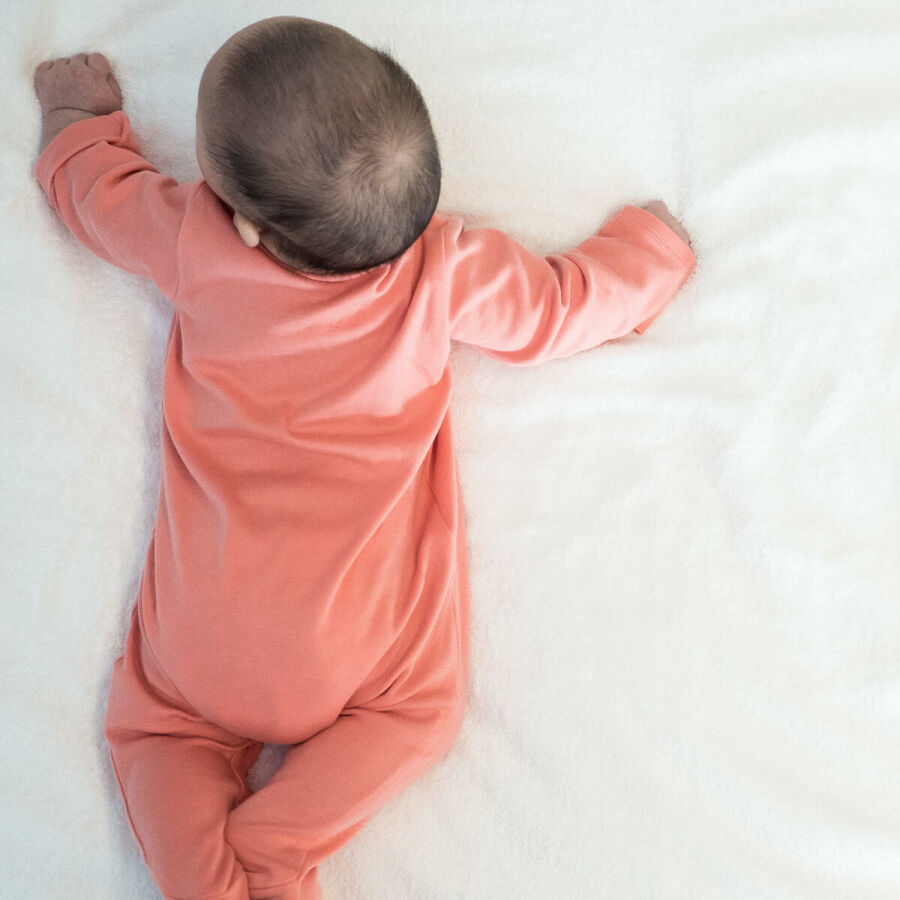Imagem vista-de-costas-de-um-bebe-sob-a-cama