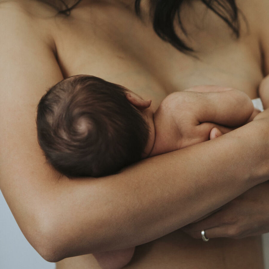 Imagem mae-despida-segurando-seu-bebe-que-mama-enquanto-ela-o-segura-em-seu-colo