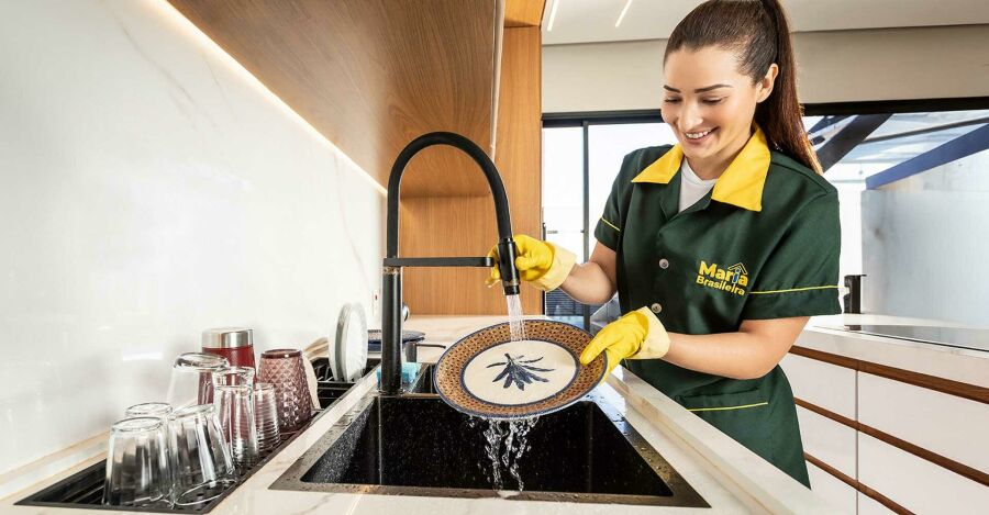 Profissional de limpeza da Maria Brasileira organizando a cozinha.