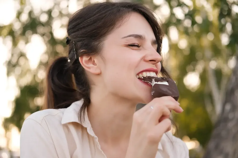 Imagem mulher-comendo-chocolate-ao-ar-livre-sorrindo